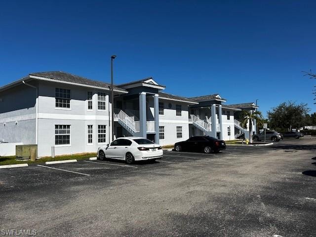 View of building exterior with stairway and uncovered parking