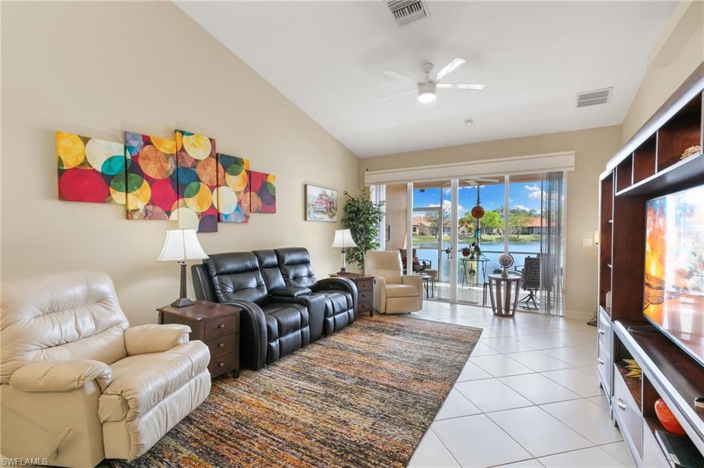 Living area featuring ceiling fan, light tile patterned floors, and vaulted ceiling
