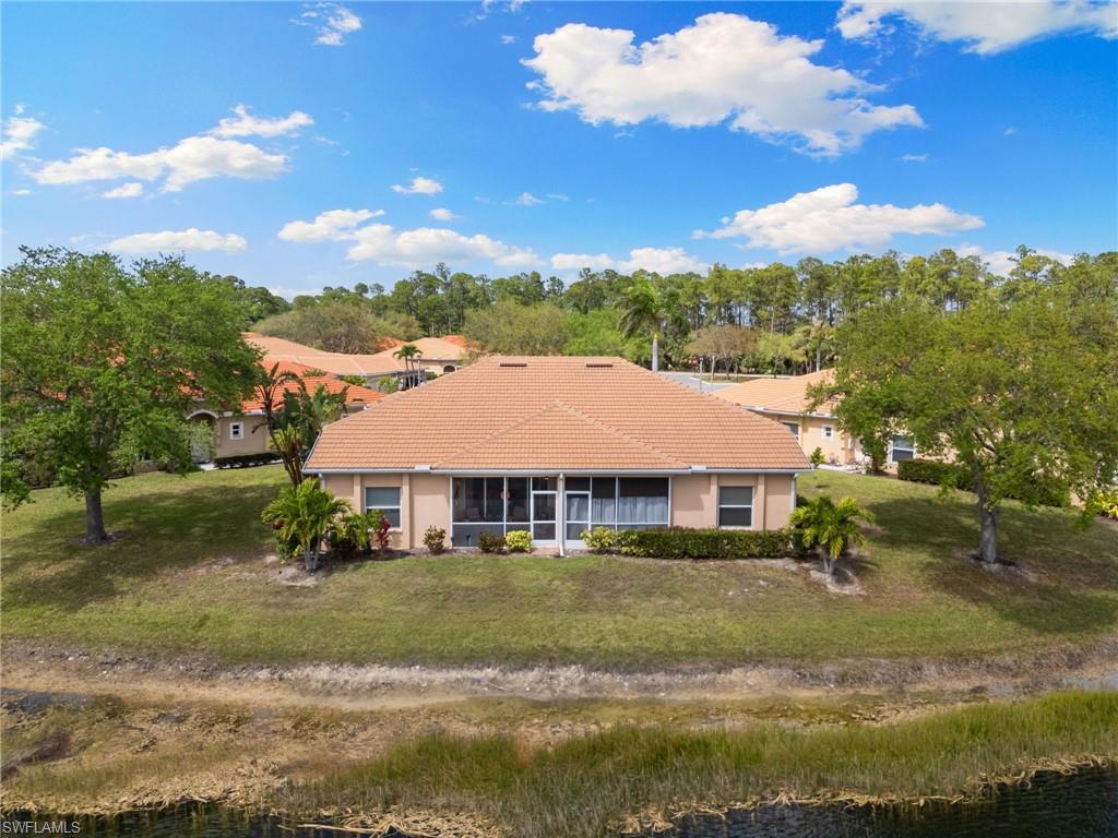 View of front of property with a tile roof, a front lawn, a water view, and a sunroom