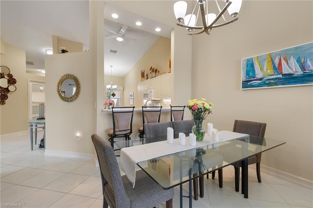 Dining room with a chandelier, a ceiling fan, light tile patterned flooring, and lofted ceiling