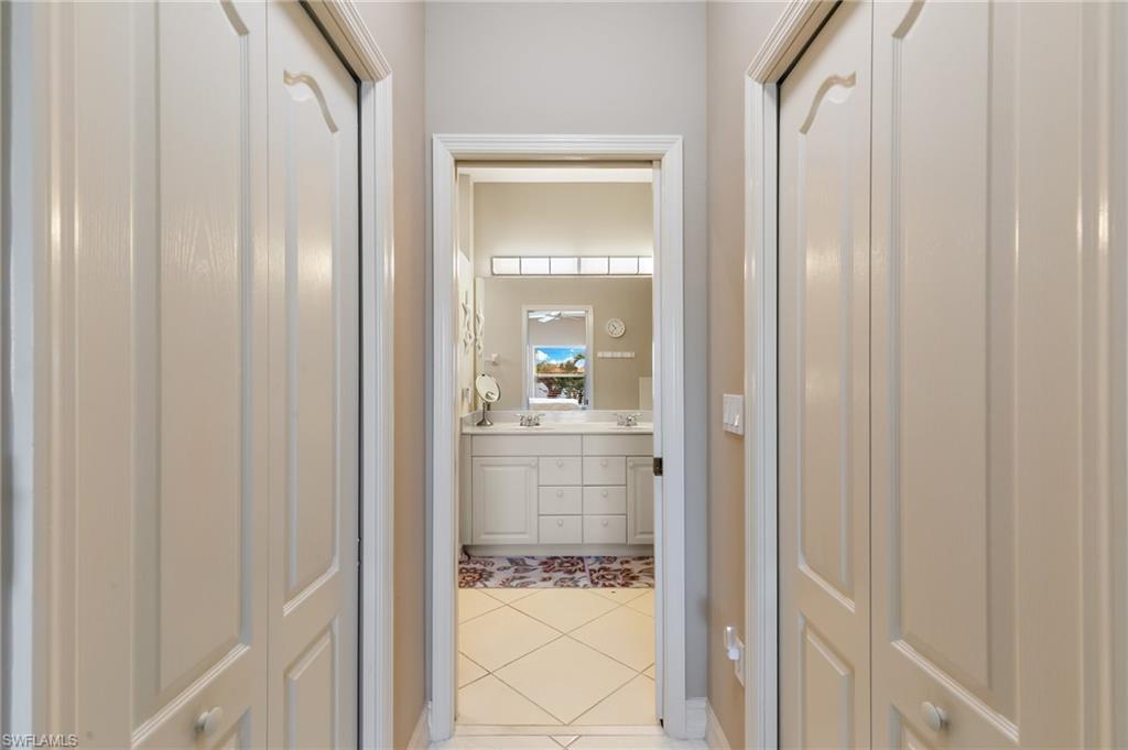 Bathroom with double vanity, light tile patterned floors, and a closet