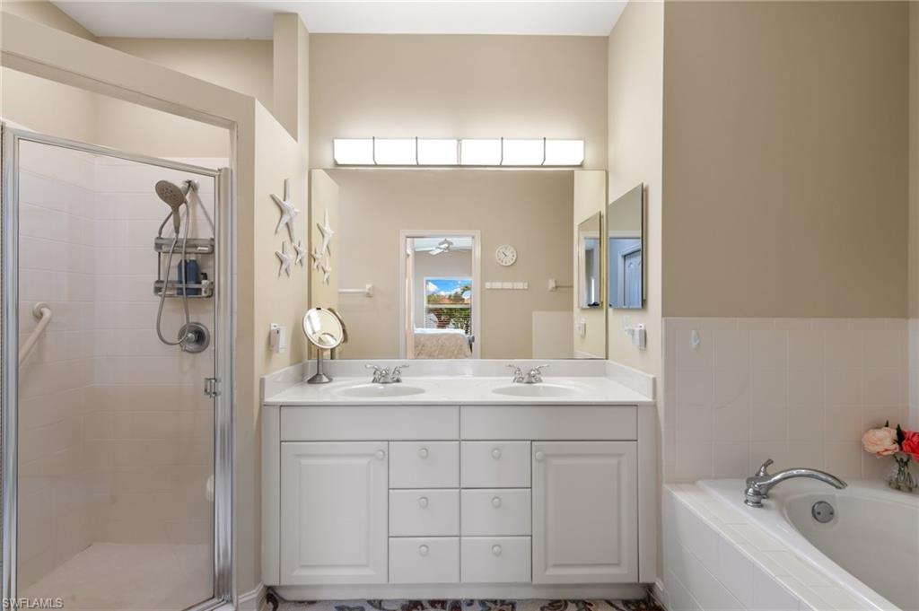 Bathroom featuring double vanity, a stall shower, and a garden tub