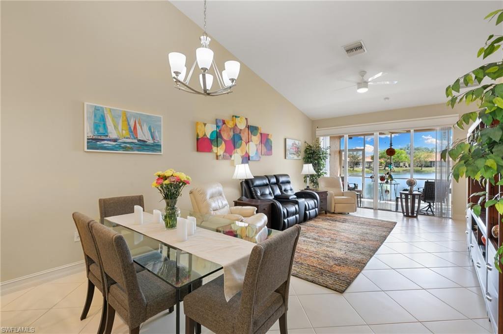 Dining area featuring a ceiling fan, vaulted ceiling, a water view, light tile patterned floors, and suspended lighting