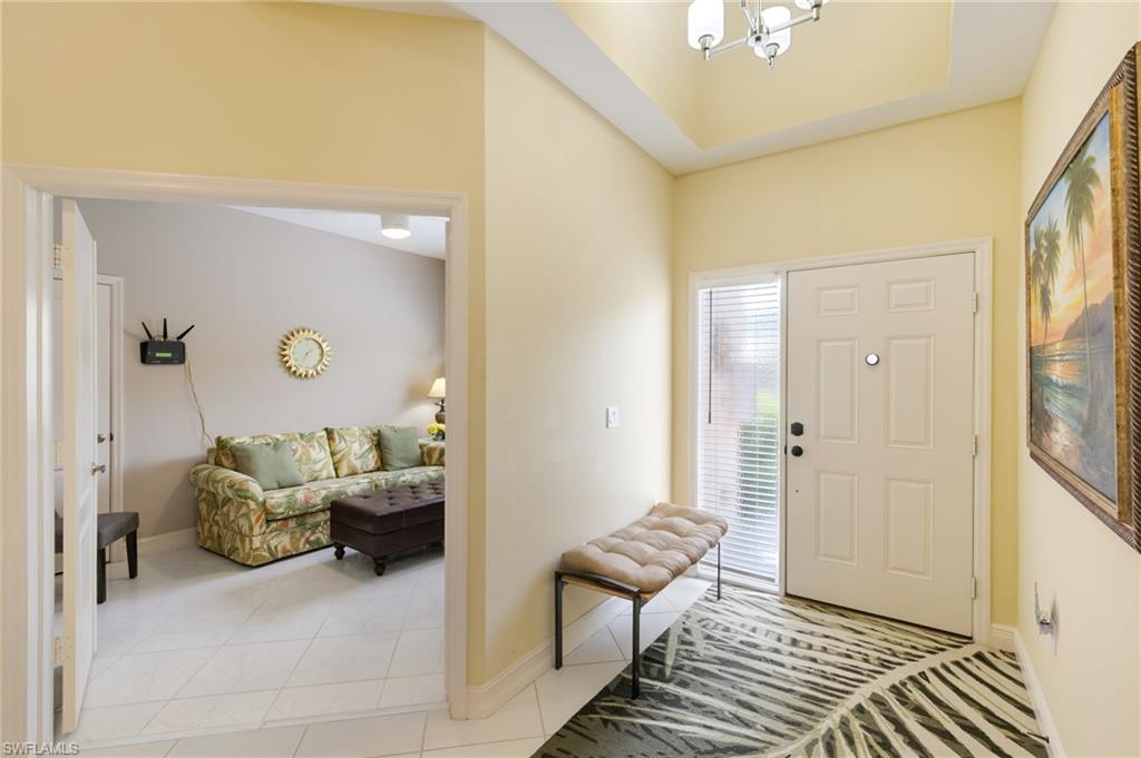 Foyer entrance with light tile patterned floors and a chandelier