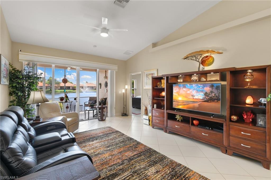Living room with a ceiling fan, light tile patterned floors, and lofted ceiling