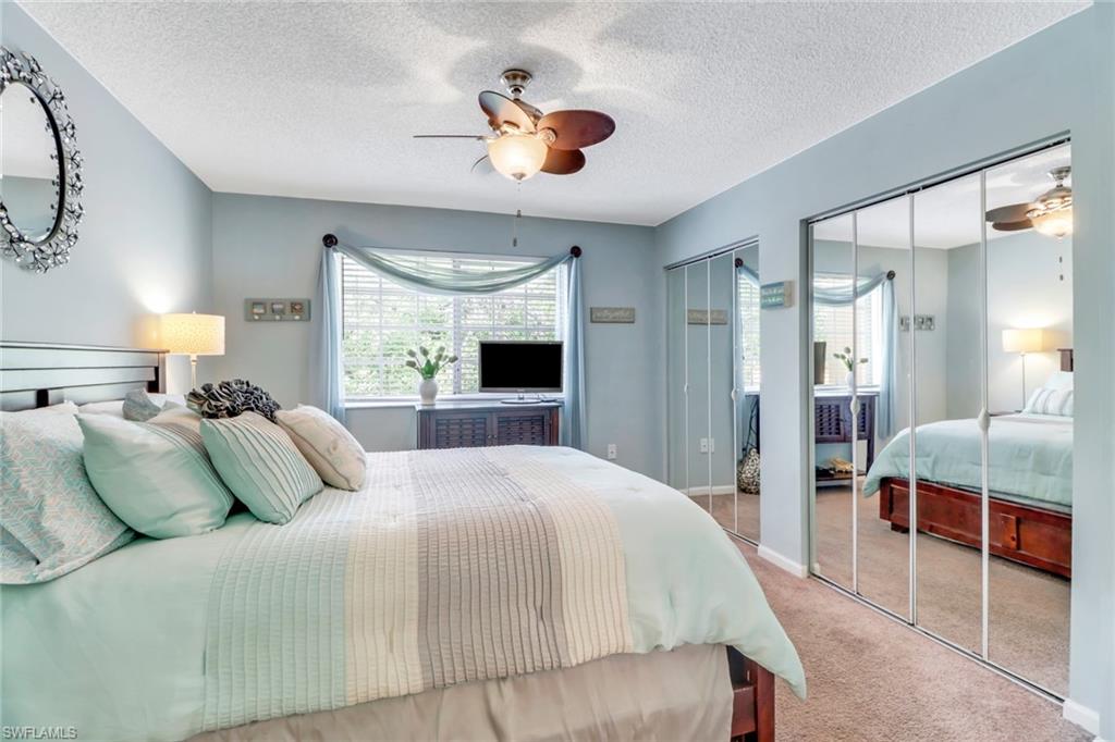 Carpeted bedroom featuring two closets, a ceiling fan, and a textured ceiling