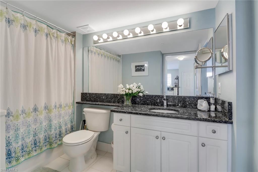 Bathroom with vanity, light tile patterned flooring, and shower / tub combo with curtain