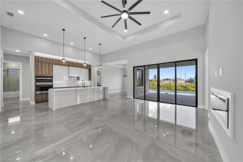 Unfurnished living room with a ceiling fan, light marble finish floors, a high ceiling, and recessed lighting