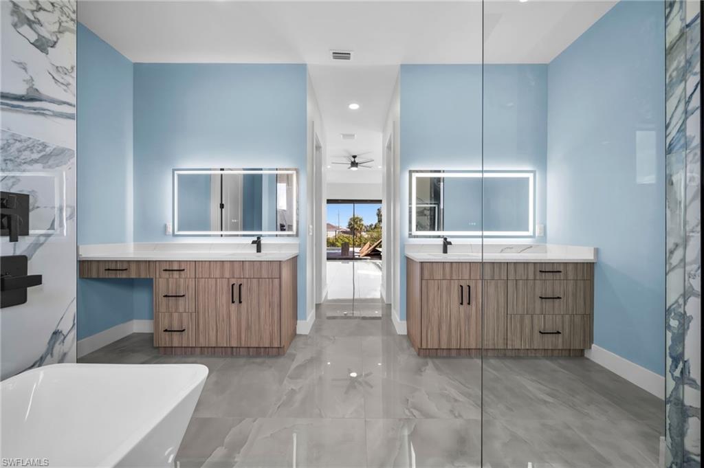 Bathroom with two vanities, ceiling fan, a freestanding bath, and recessed lighting