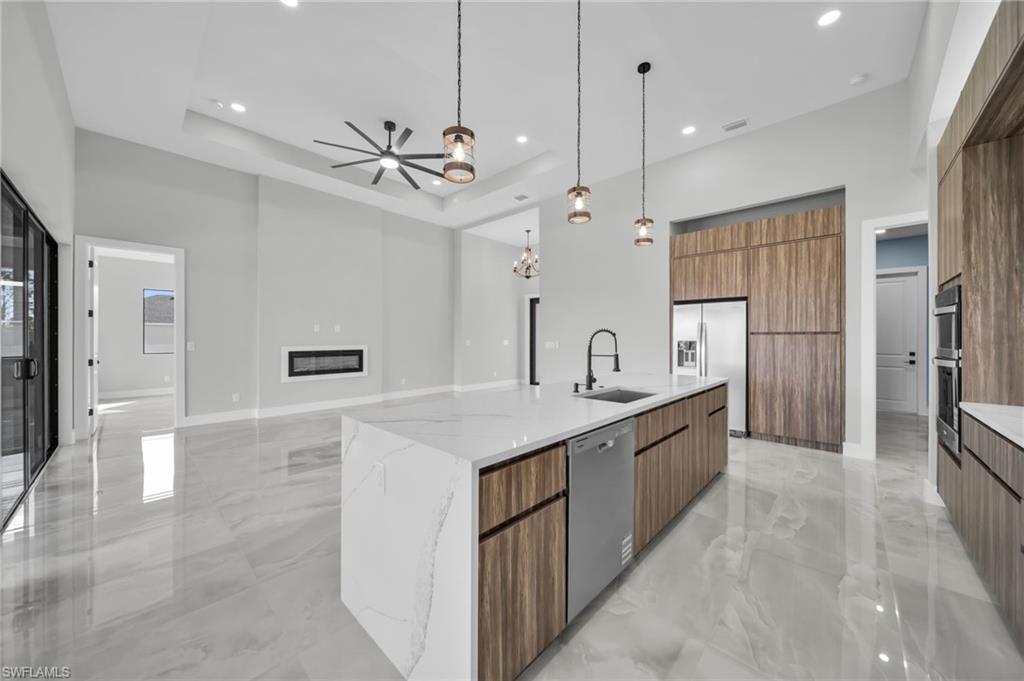 Kitchen featuring modern cabinets, light stone counters, a spacious island, light marble finish flooring, and wood finish cabinetry