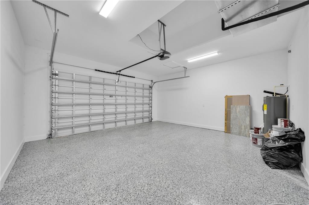 Garage featuring baseboards and electric water heater