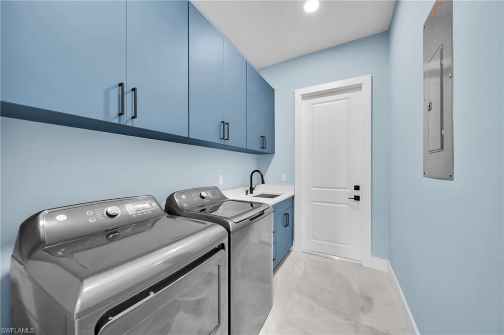Laundry room with washing machine and clothes dryer, cabinet space, and electric panel