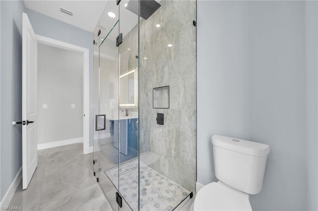 Bathroom with a marble finish shower and recessed lighting