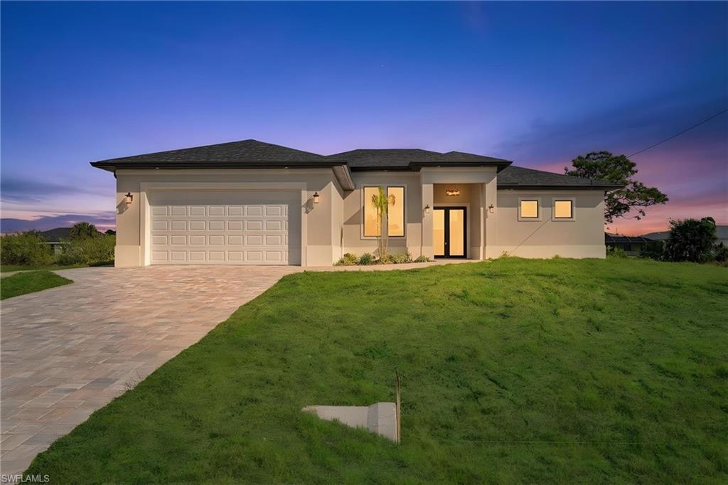 Prairie-style house with a front yard, an attached garage, stucco siding, and driveway