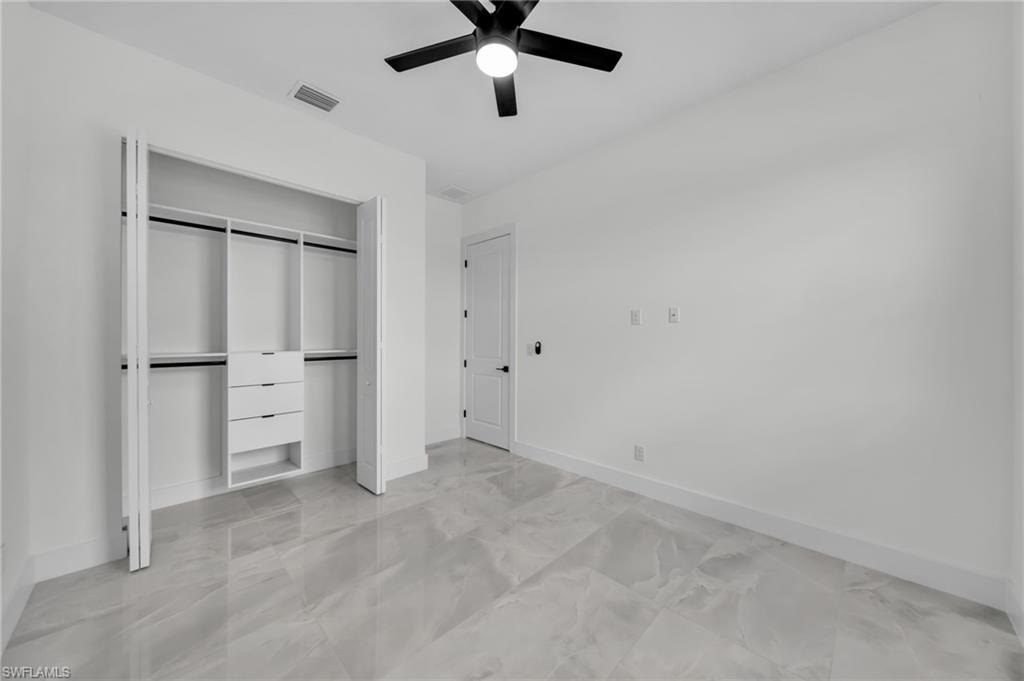 Unfurnished bedroom featuring a closet, a ceiling fan, and light marble finish floors