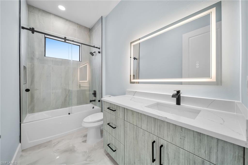 Bathroom with vanity, combined bath / shower with glass door, recessed lighting, and light marble finish floors
