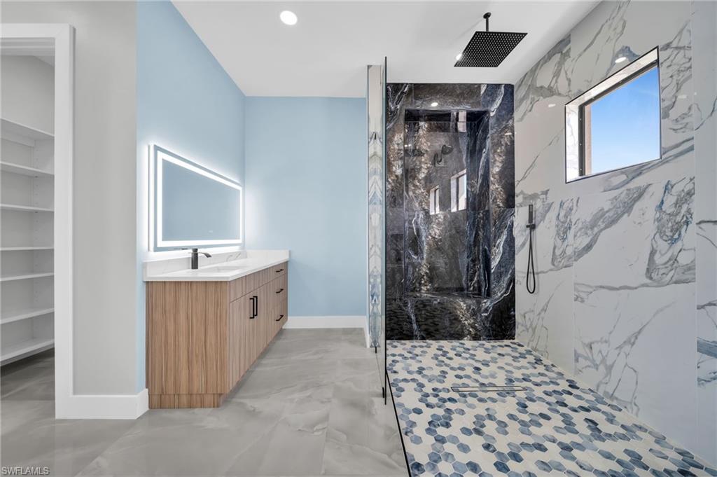 Full bathroom featuring vanity, a marble finish shower, and finished concrete floors