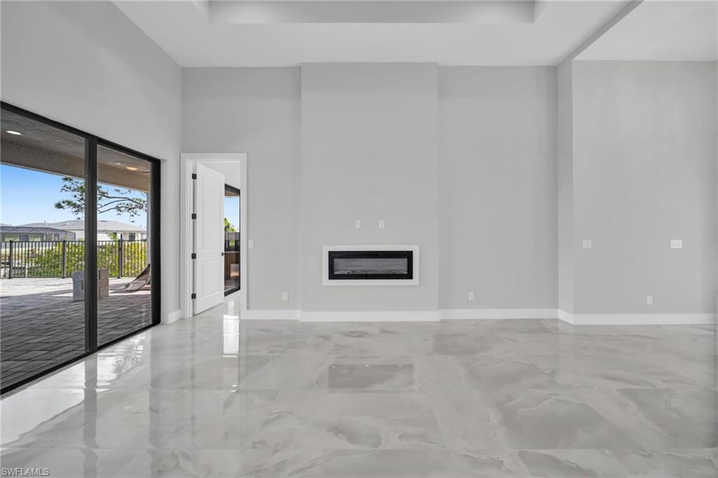 Unfurnished living room featuring a glass covered fireplace and a high ceiling