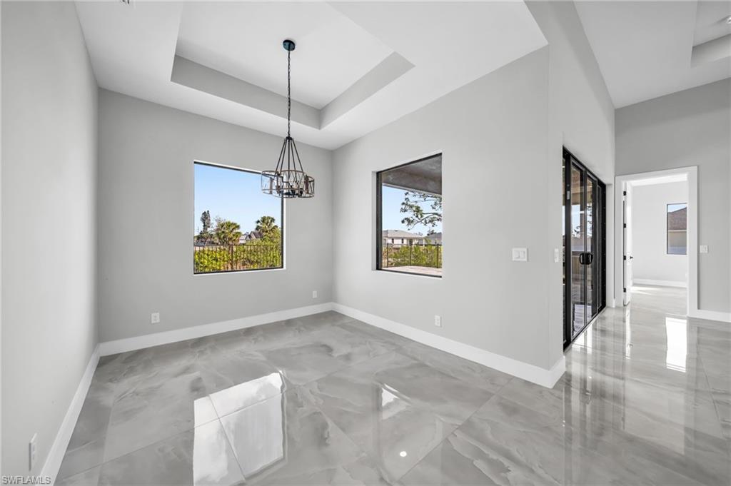 Unfurnished dining area with a raised ceiling and a chandelier