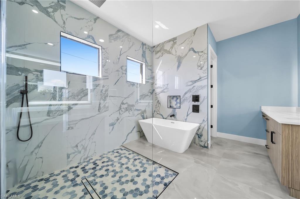 Full bathroom with vanity, a soaking tub, and a marble finish shower