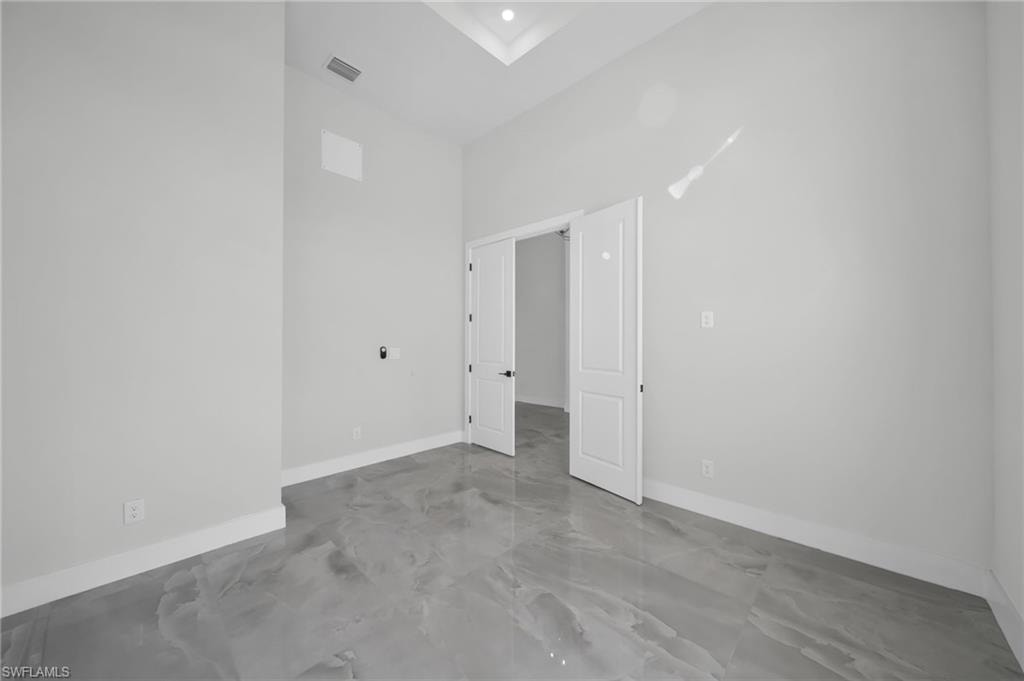 Unfurnished room with baseboards and a high ceiling