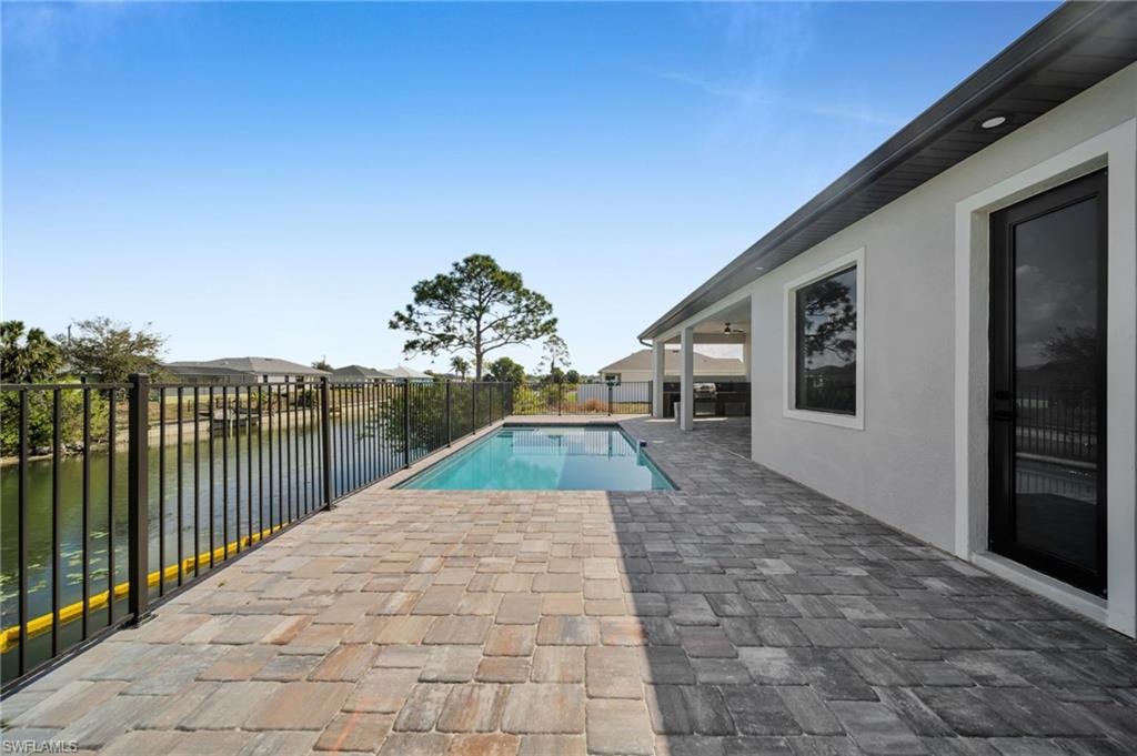 View of pool with patio surround, a fenced backyard, and a water view