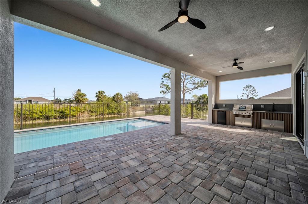 View of swimming pool featuring area for grilling, patio surround, and a fenced backyard
