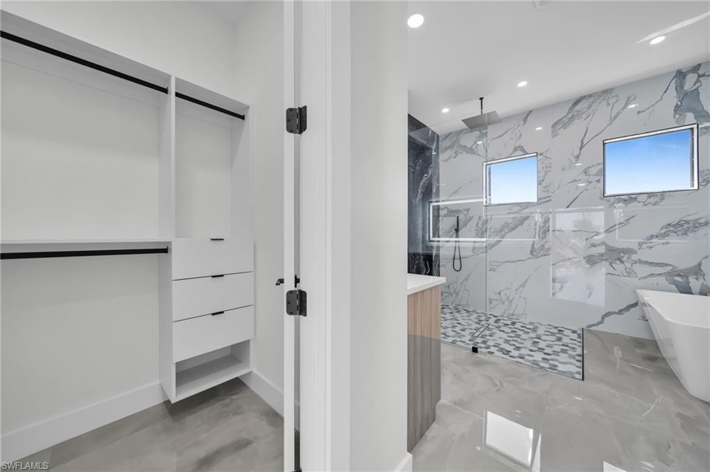 Full bath featuring a marble finish shower, a freestanding tub, recessed lighting, vanity, and light marble finish floors