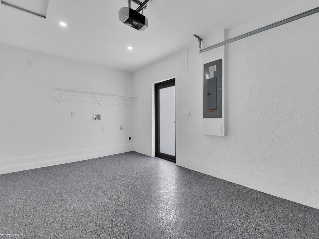 Garage featuring electric panel, a garage door opener, and recessed lighting