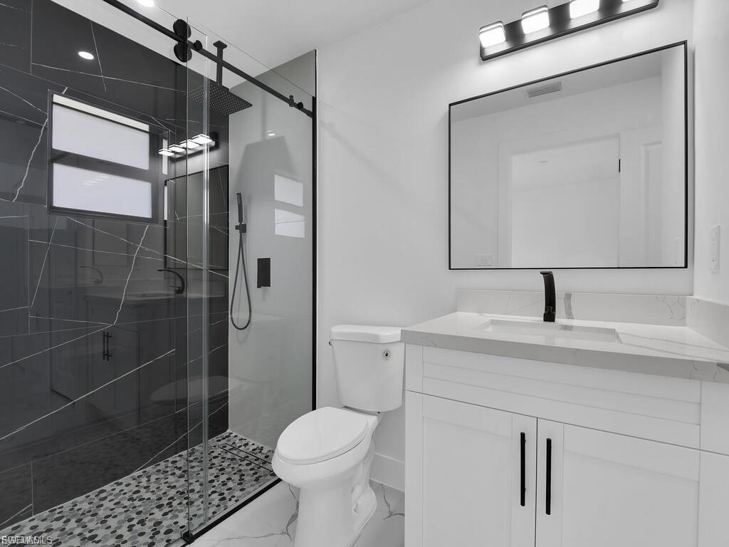 Full bathroom with vanity, a stall shower, and light marble finish flooring