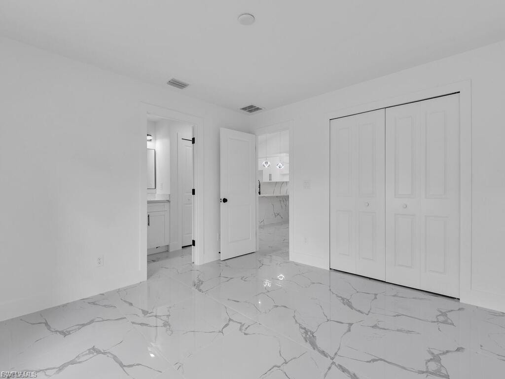 Unfurnished bedroom with a closet and light marble finish floors