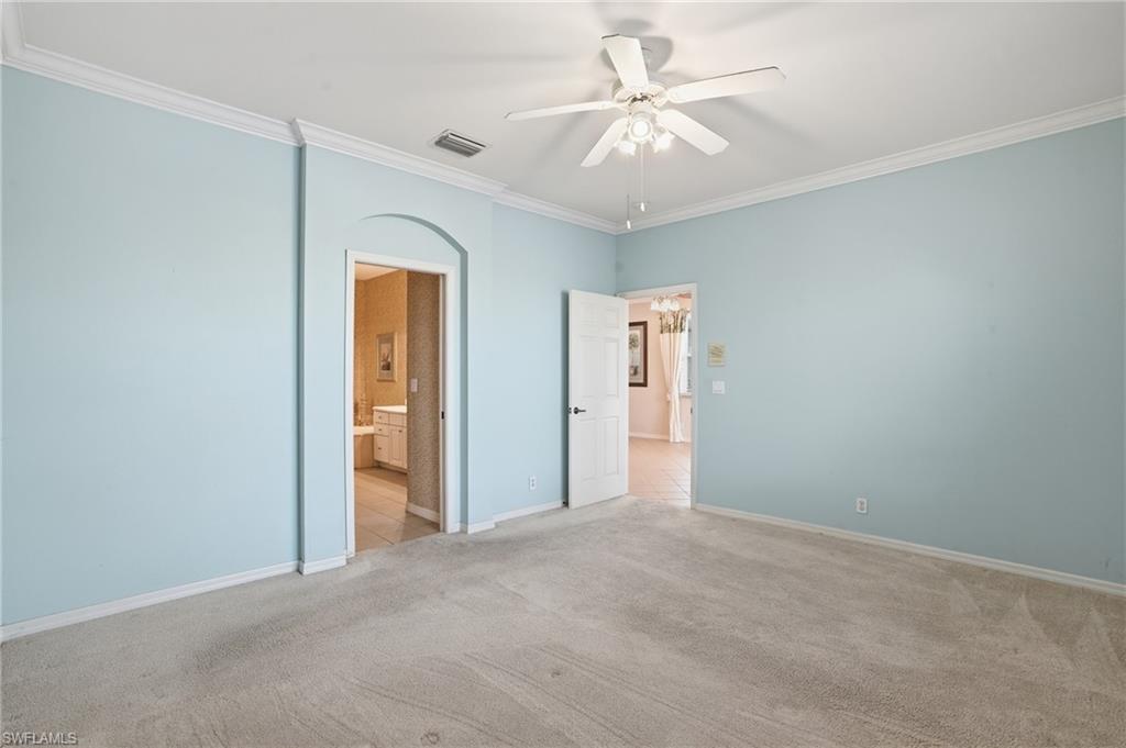 Unfurnished bedroom with ornamental molding, a ceiling fan, light carpet, and ensuite bathroom - Virtually Edited Image