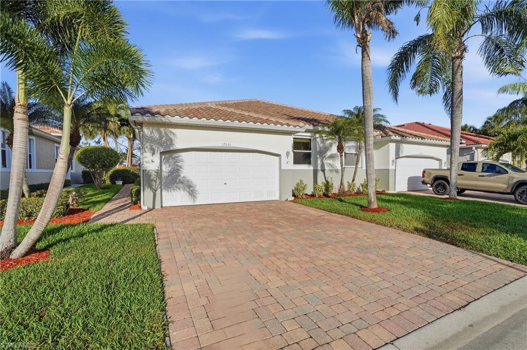 View of front of house featuring stucco siding, decorative driveway, a front yard, a garage, and a tiled roof - Virtually Edited Image