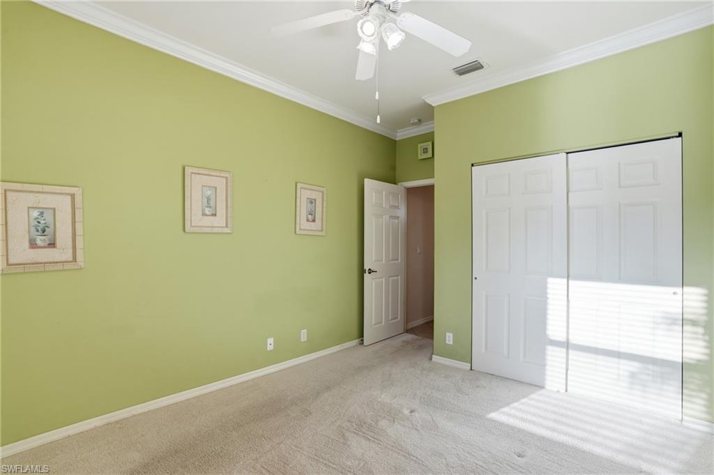 Unfurnished bedroom featuring crown molding, carpet, ceiling fan, and a closet - Virtually Edited Image