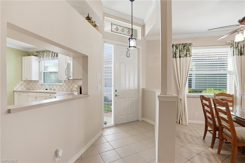 Entrance foyer with crown molding, light tile patterned flooring, and ceiling fan - Virtually Edited Image