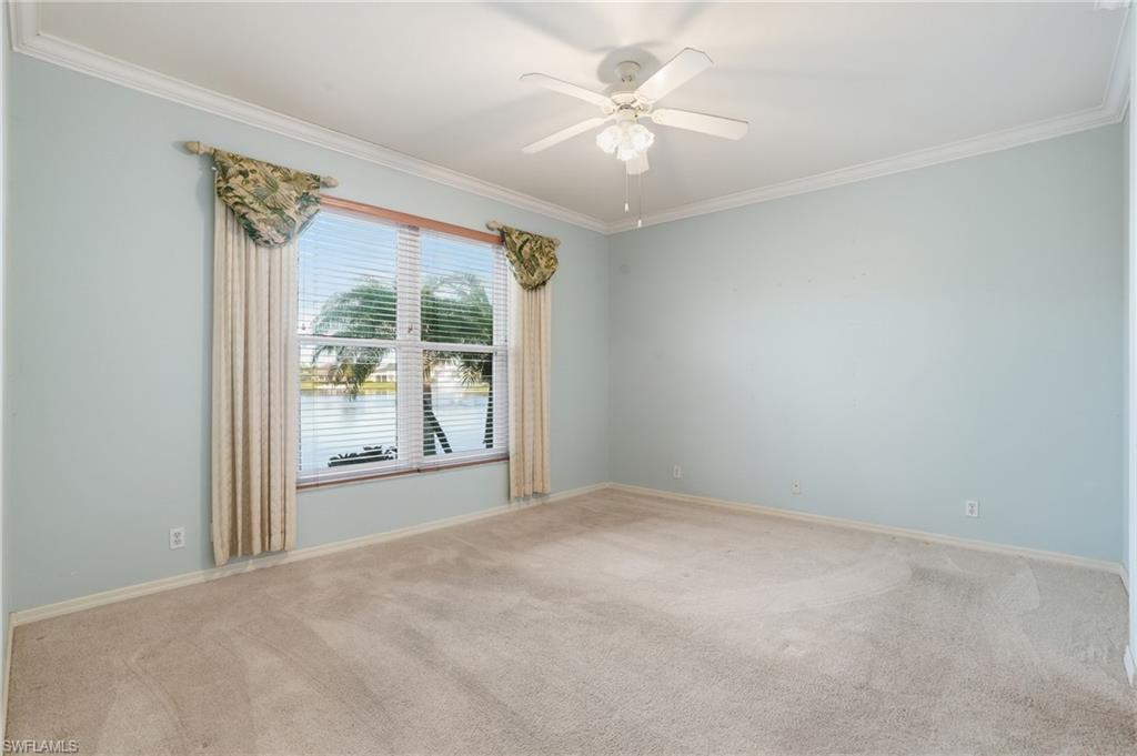 Unfurnished room with light carpet, ornamental molding, ceiling fan, and a water view - Virtually Edited Image
