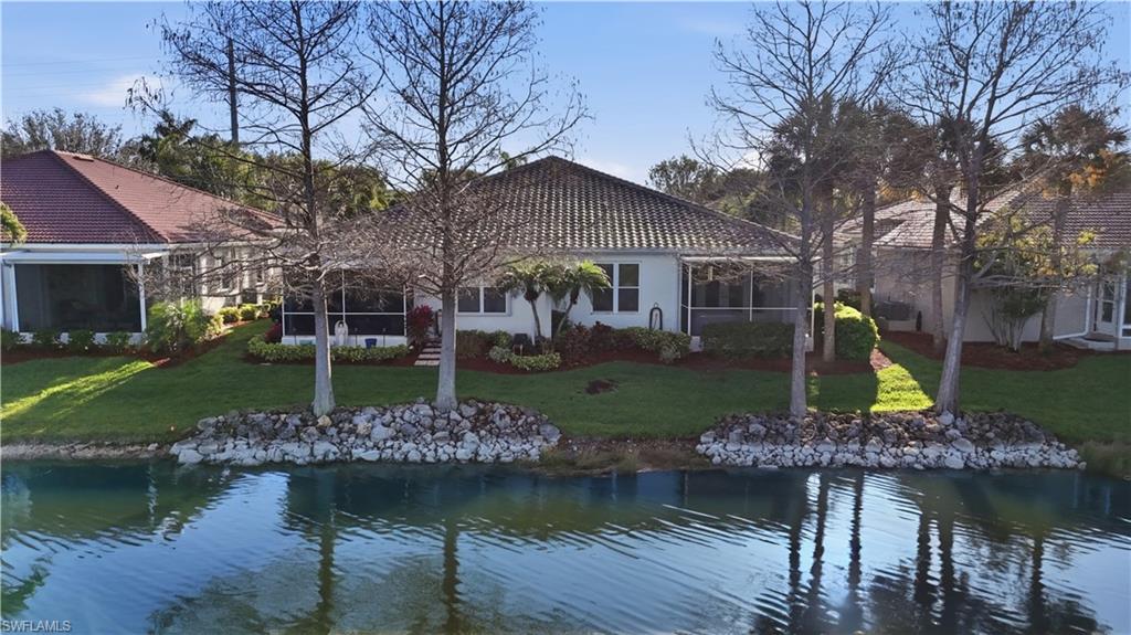 Rear view of property featuring a sunroom, a water view, and a lawn - Virtually Edited Image