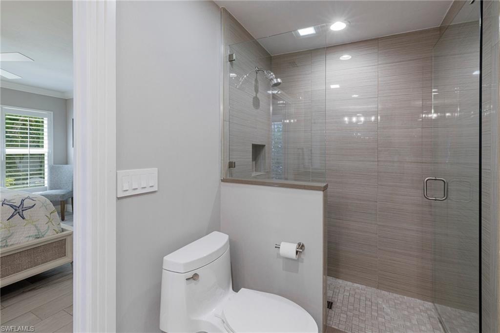 Bathroom featuring walk in shower, ornamental molding, and toilet