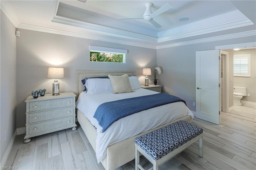 Bedroom featuring ceiling fan, a tray ceiling, and light wood-type flooring