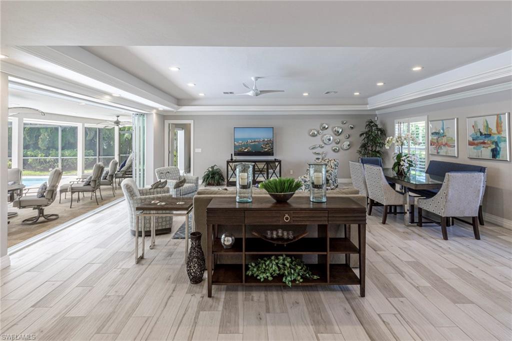Dining room featuring light wood-type flooring, ornamental molding, ceiling fan, and a raised ceiling