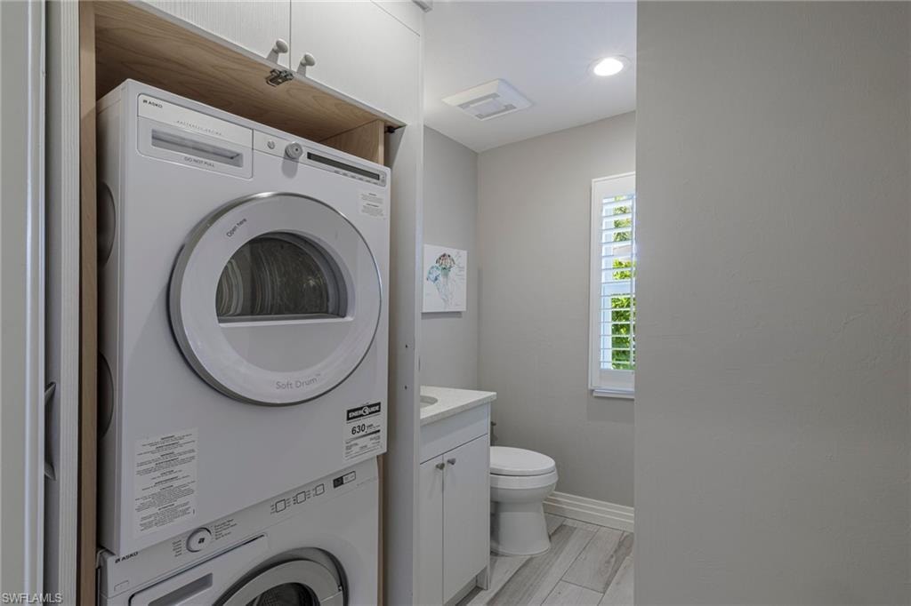 Laundry room featuring light hardwood / wood-style floors and stacked washer and dryer
