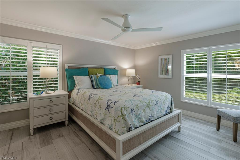 Bedroom featuring ceiling fan, multiple windows, and hardwood / wood-style floors