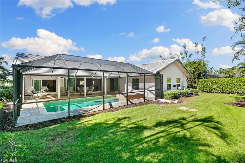 Back of house with a lanai, a fenced in pool, a patio area, an outdoor hangout area, and a lawn