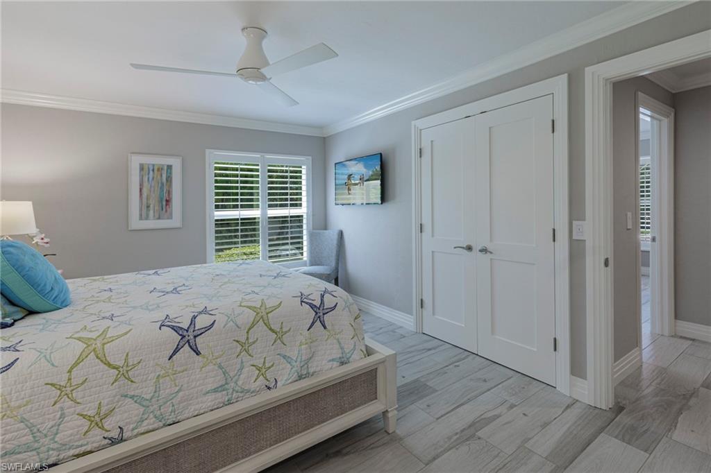 Bedroom featuring light hardwood / wood-style flooring, a closet, ceiling fan, and ornamental molding