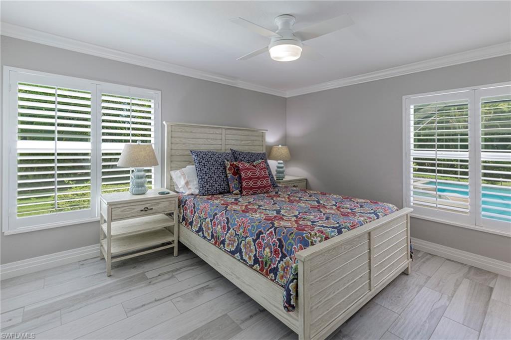 Bedroom featuring ceiling fan, multiple windows, light hardwood / wood-style floors, and ornamental molding