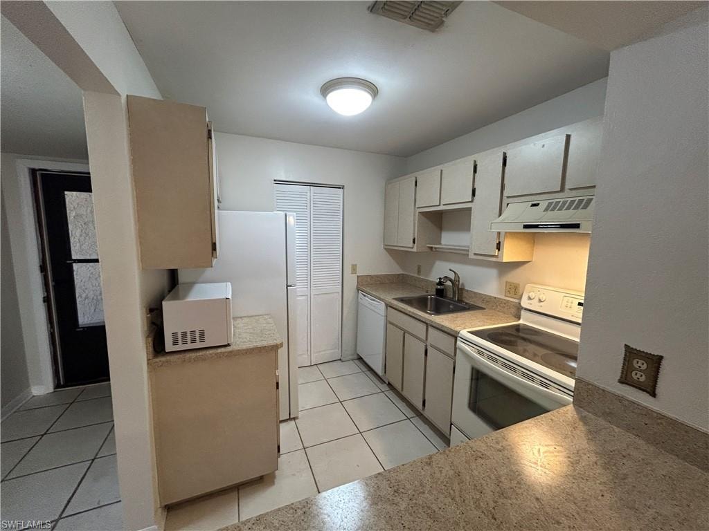 Kitchen featuring white appliances, exhaust hood, light countertops, and light tile patterned floors