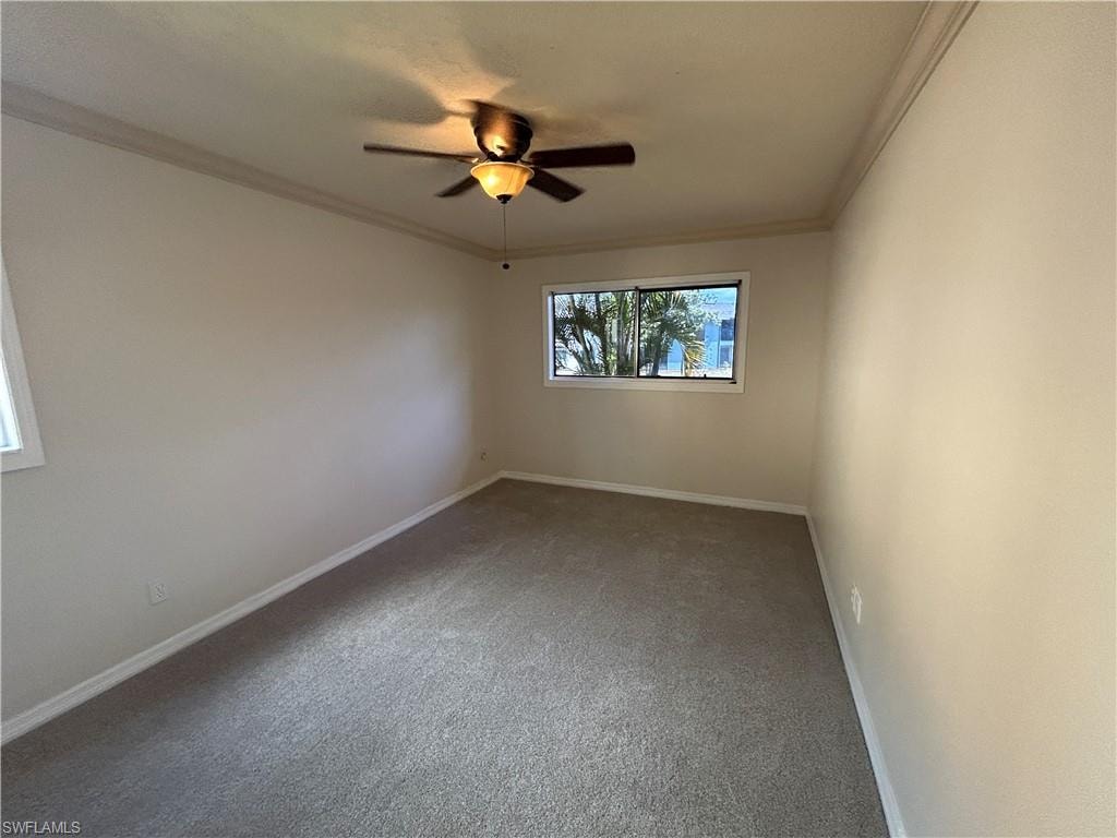 Carpeted empty room with crown molding and a ceiling fan