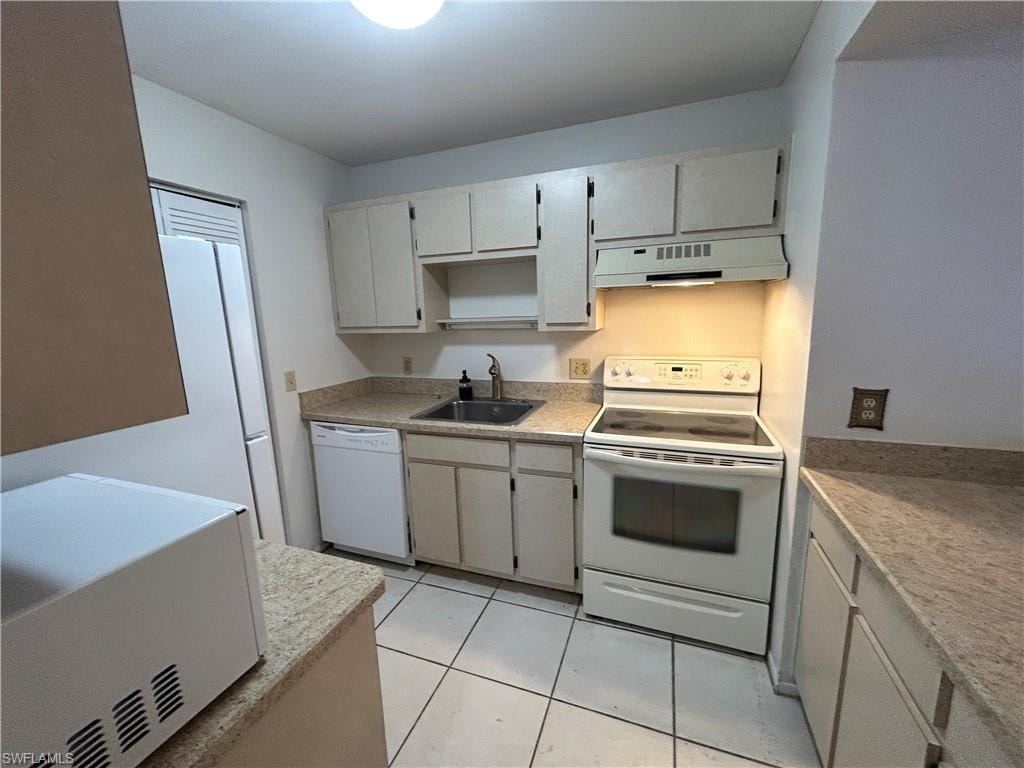 Kitchen featuring white appliances, ventilation hood, and light tile patterned flooring