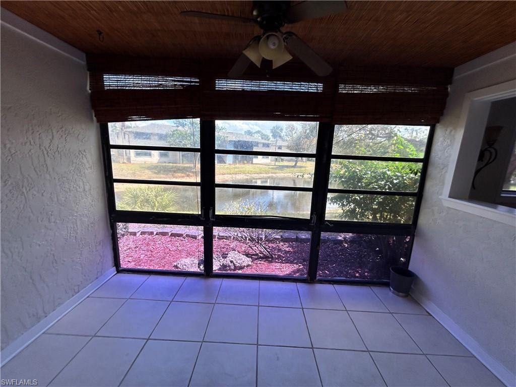 Unfurnished sunroom with a ceiling fan and a water view