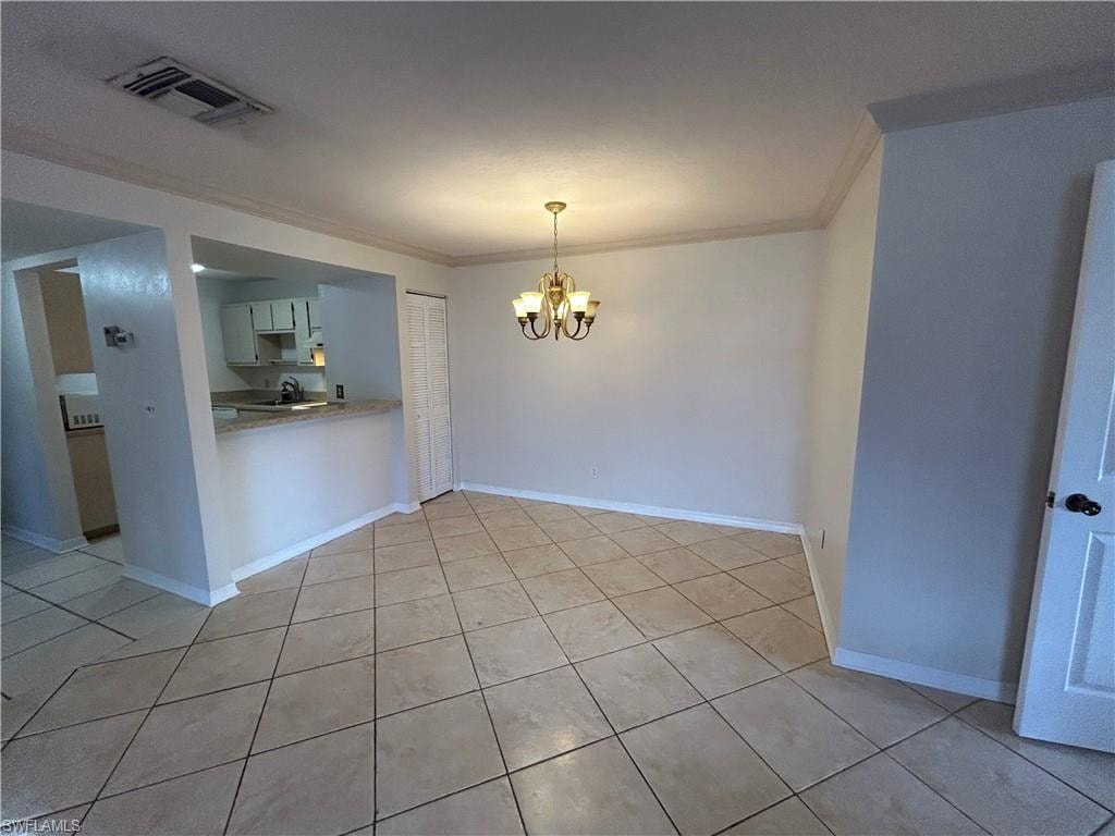 Unfurnished dining area with crown molding, hanging lights, and light tile patterned floors